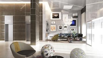 A modern lobby with a seating area, a staircase, and a wall with framed pictures.