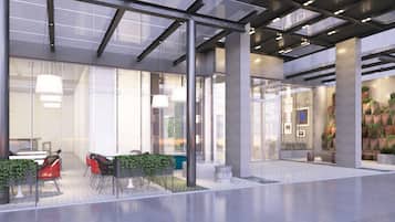 A modern lobby with glass walls, seating areas, and indoor plants.