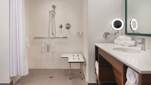 Ein modernes Badezimmer mit Dusche, Waschtisch und Spiegel sowie einem Handtuchhalter.