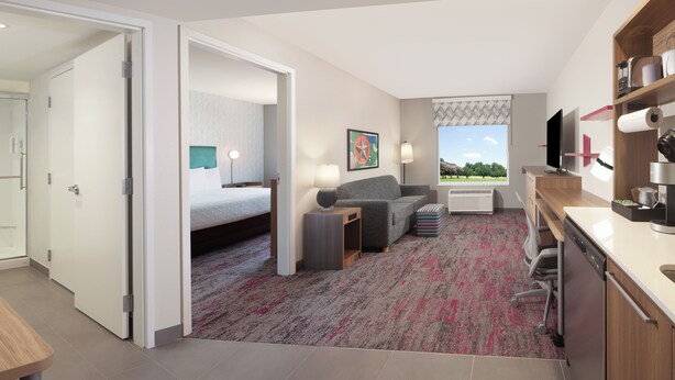 Ein modernes Hotelzimmer mit Bett, Sofa, Schreibtisch und Blick ins Freie.