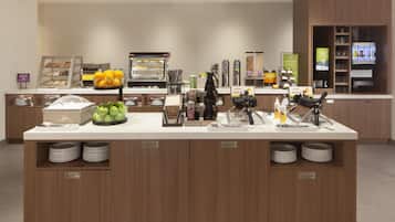 A self-service breakfast station with various food options, including waffles, fruits, and beverages.