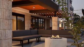 An outdoor seating area with a fire pit and a modern building in the background.