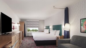 Ein Hotelzimmer mit Bett, Fernseher, Schreibtisch und einer Couch.