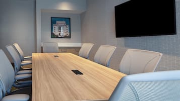 A conference room with a long table, six chairs, a mounted television, and a framed picture on the wall.