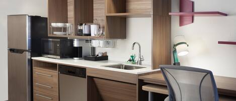 A modern kitchen with a built-in dishwasher, a refrigerator, a microwave, and a coffee machine.
