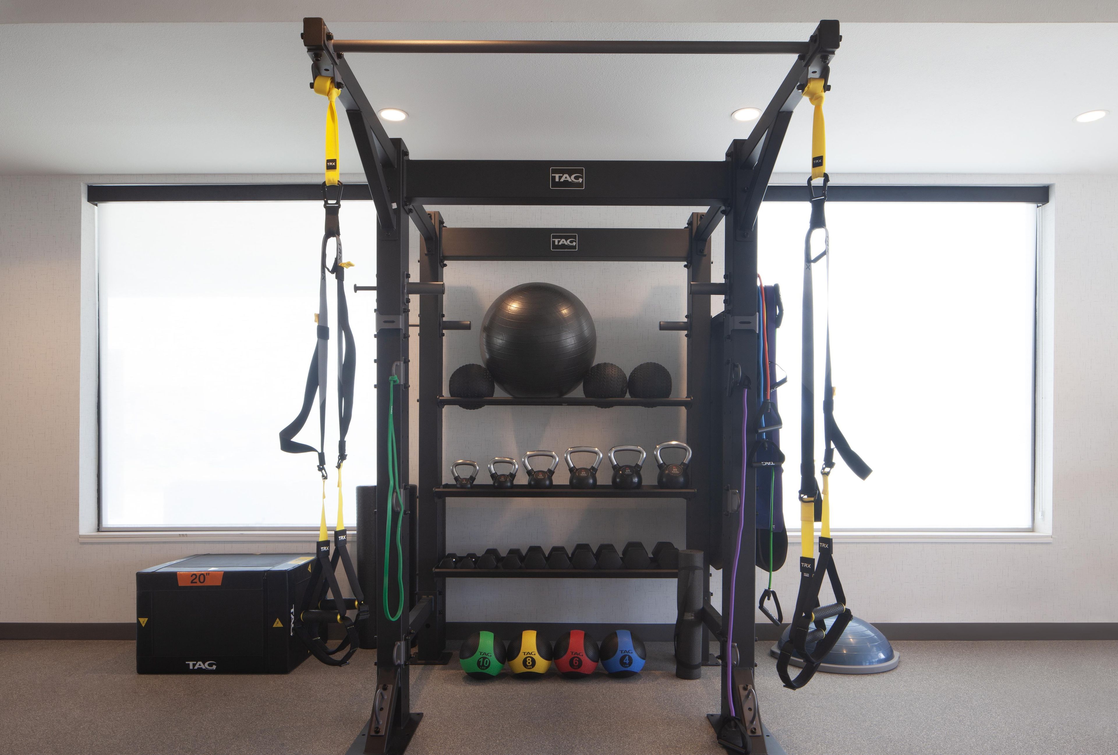 A gym with a TRX suspension trainer, kettlebells, medicine balls, and dumbbells.