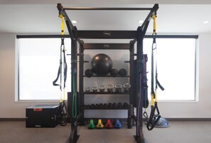 Een sportschool met een TRX-opstelling, kettlebells, medicine ballen en gewichten.