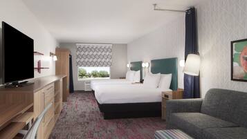 A hotel room with a bed, a TV, a desk, and a sofa.