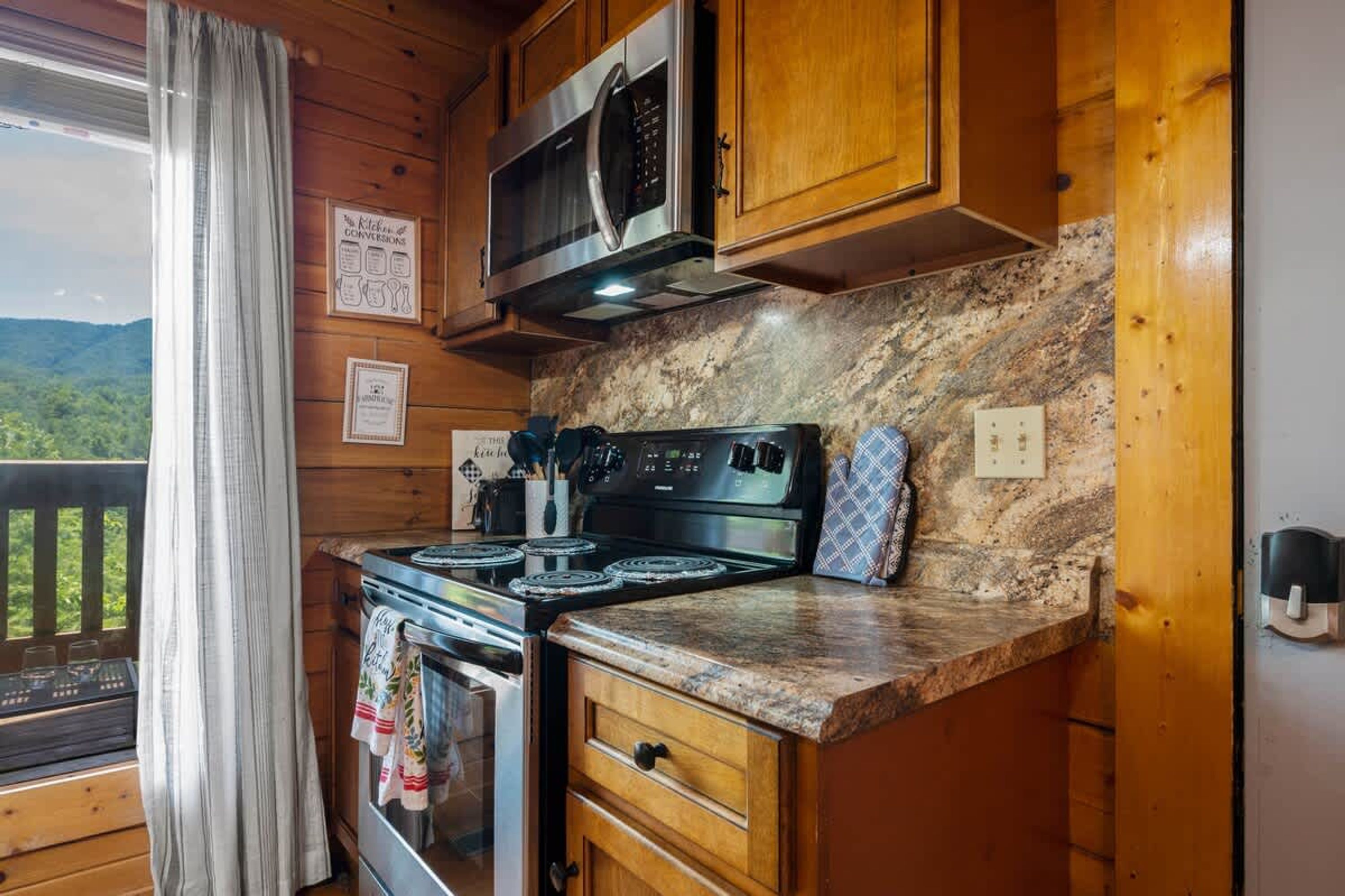 Una cocina con armarios de madera, encimera de granito, estufa y microondas.
