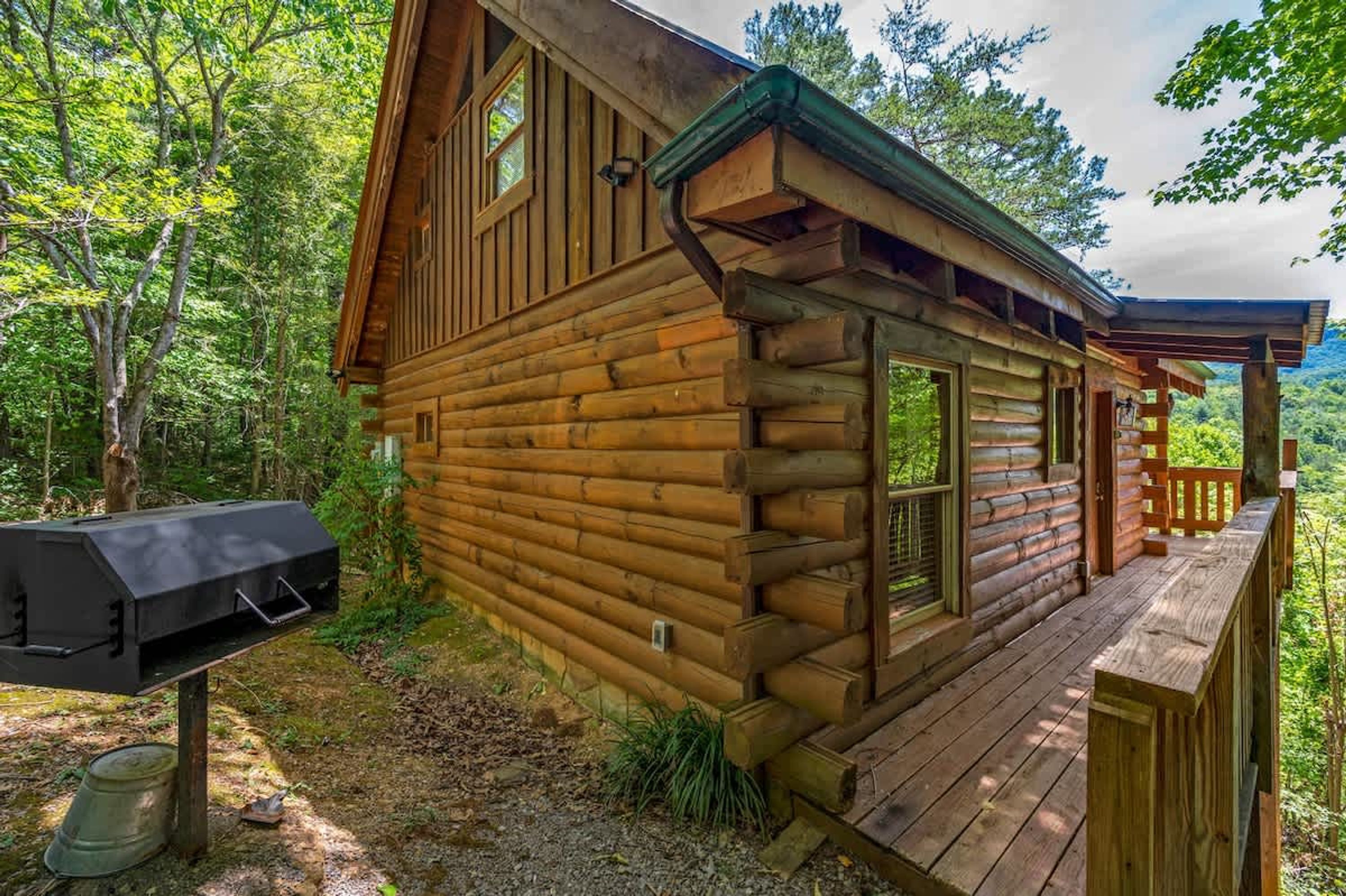 A log cabin with a deck and a grill.