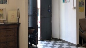 Een gang met een geruite vloer, een houten kast en een deur naar een andere kamer.