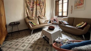 Een woonkamer met een bank, een fauteuil, een bijzettafeltje en een vloer met een patroon.