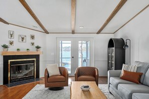 A living room with a fireplace, leather sofas, a coffee table, and a view of the outdoors. - Lakescape on Lake Murray w/Private Dock- Leesville (Leesville)
