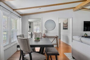 A dining area with a wooden table, chairs, and a bench. There is a round mirror on the wall, a lamp, and a television mounted on the wall. - Lakescape on Lake Murray w/Private Dock- Leesville (Leesville)
