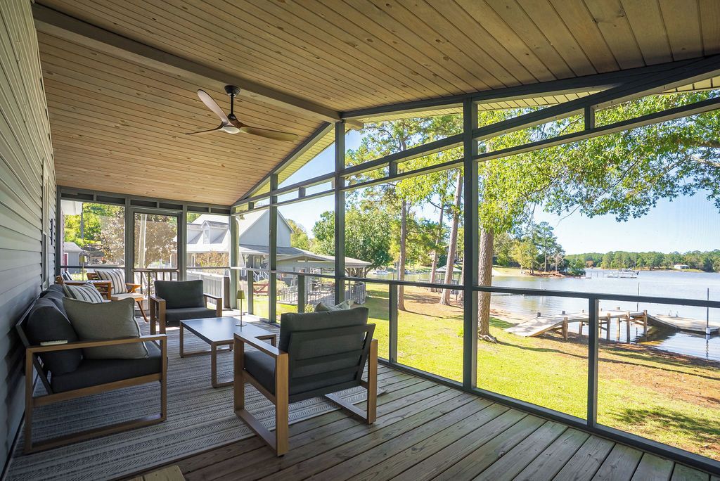 A covered outdoor seating area with a view of a lake and dock.