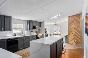 A modern kitchen with dark cabinets, a marble island, and a herringbone wood wall. - Lakescape on Lake Murray w/Private Dock- Leesville (Leesville)