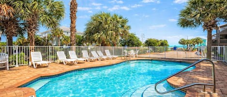 A swimming pool with lounge chairs and palm trees.