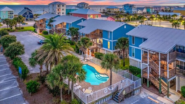 Un hotel sulla costa con edifici a più piani, una piscina e vista sull'oceano.
