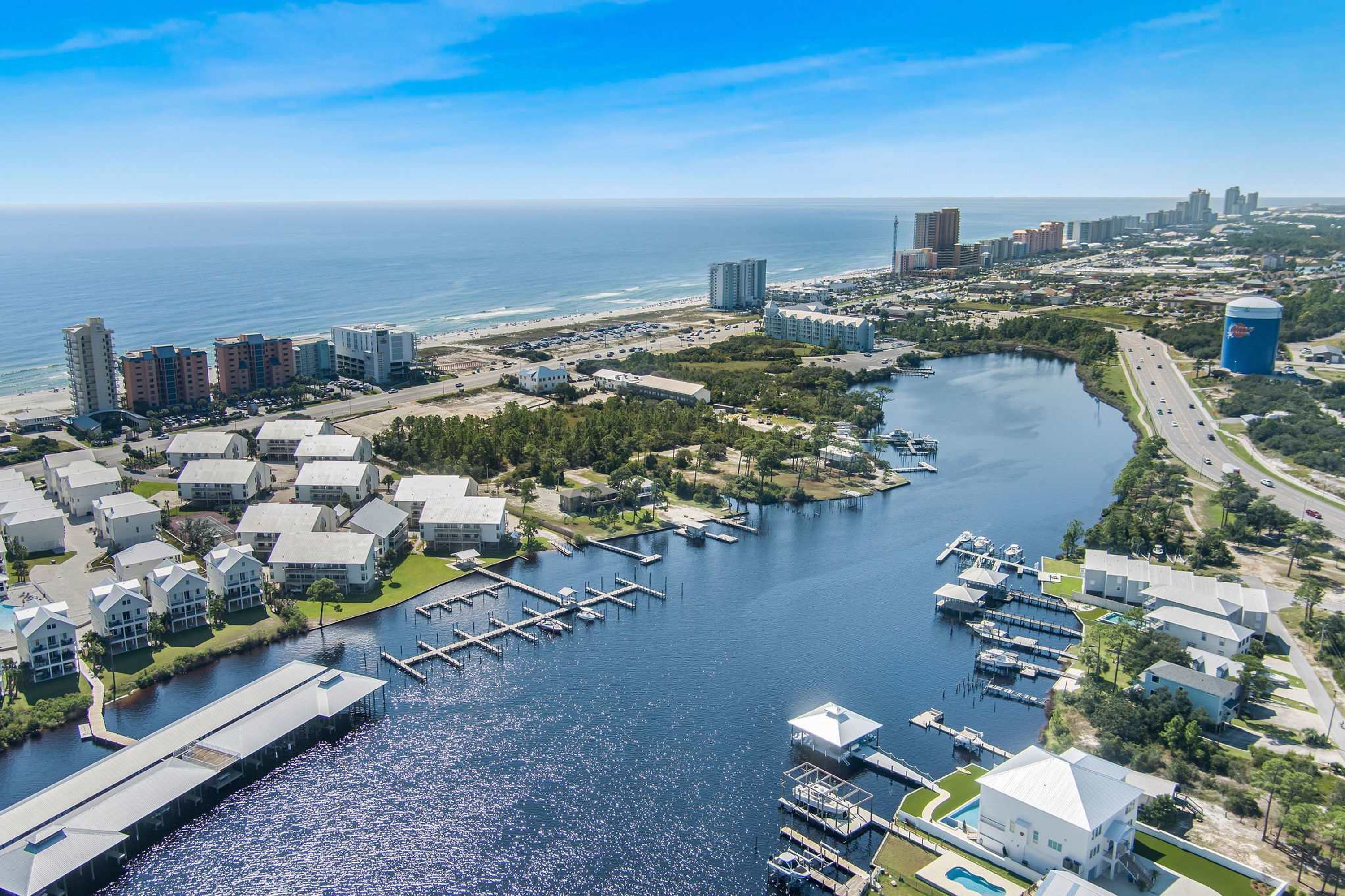 An aerial view of a coastal area with a marina, residential buildings, and a large body of water.