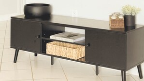 Ein schwarzes Konsolentisch mit einem gewobenen Korb, einer schwarzen Schale und einem kleinen Topfpflanzen.