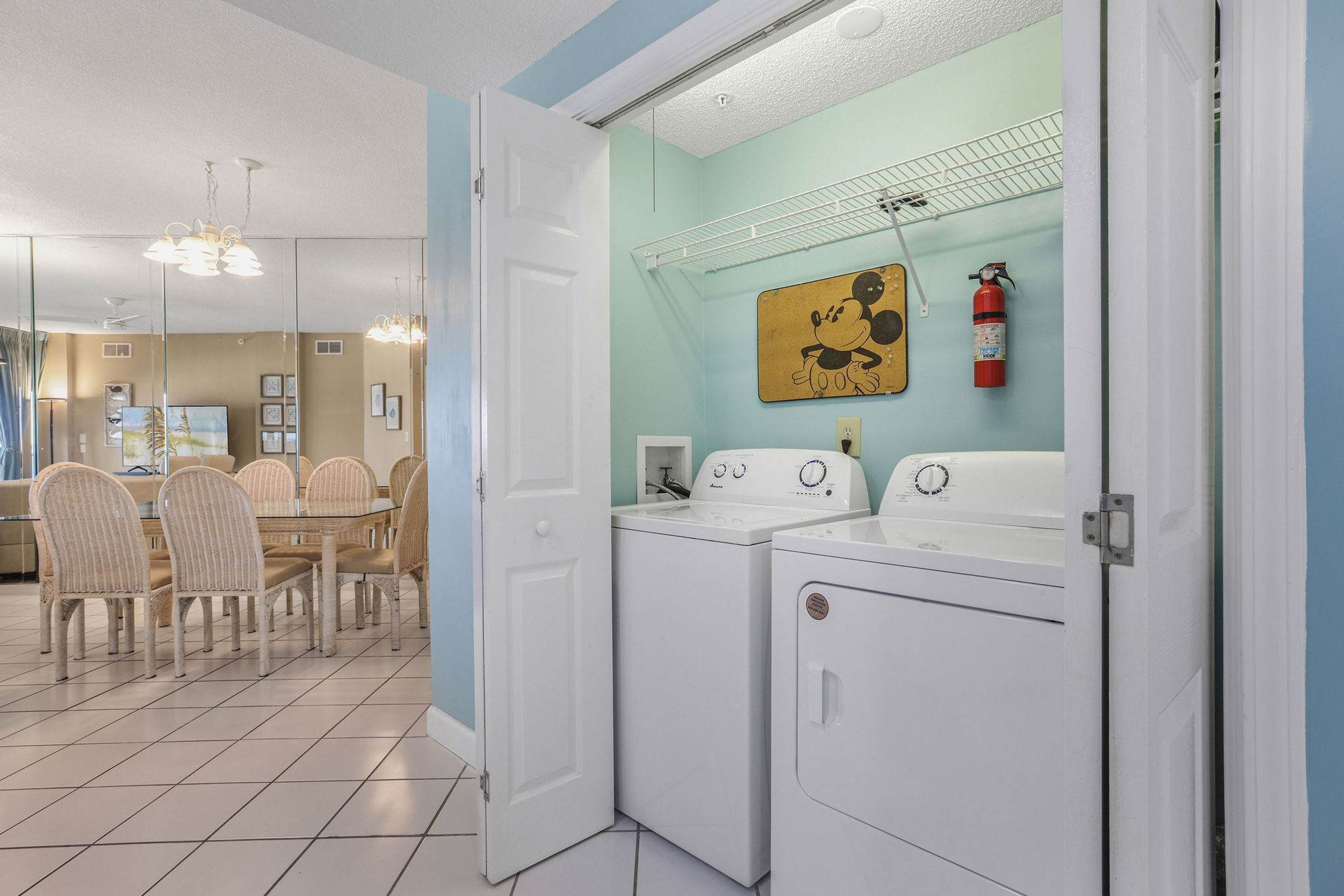 A laundry area with a washing machine, dryer, and a fire extinguisher on the wall.