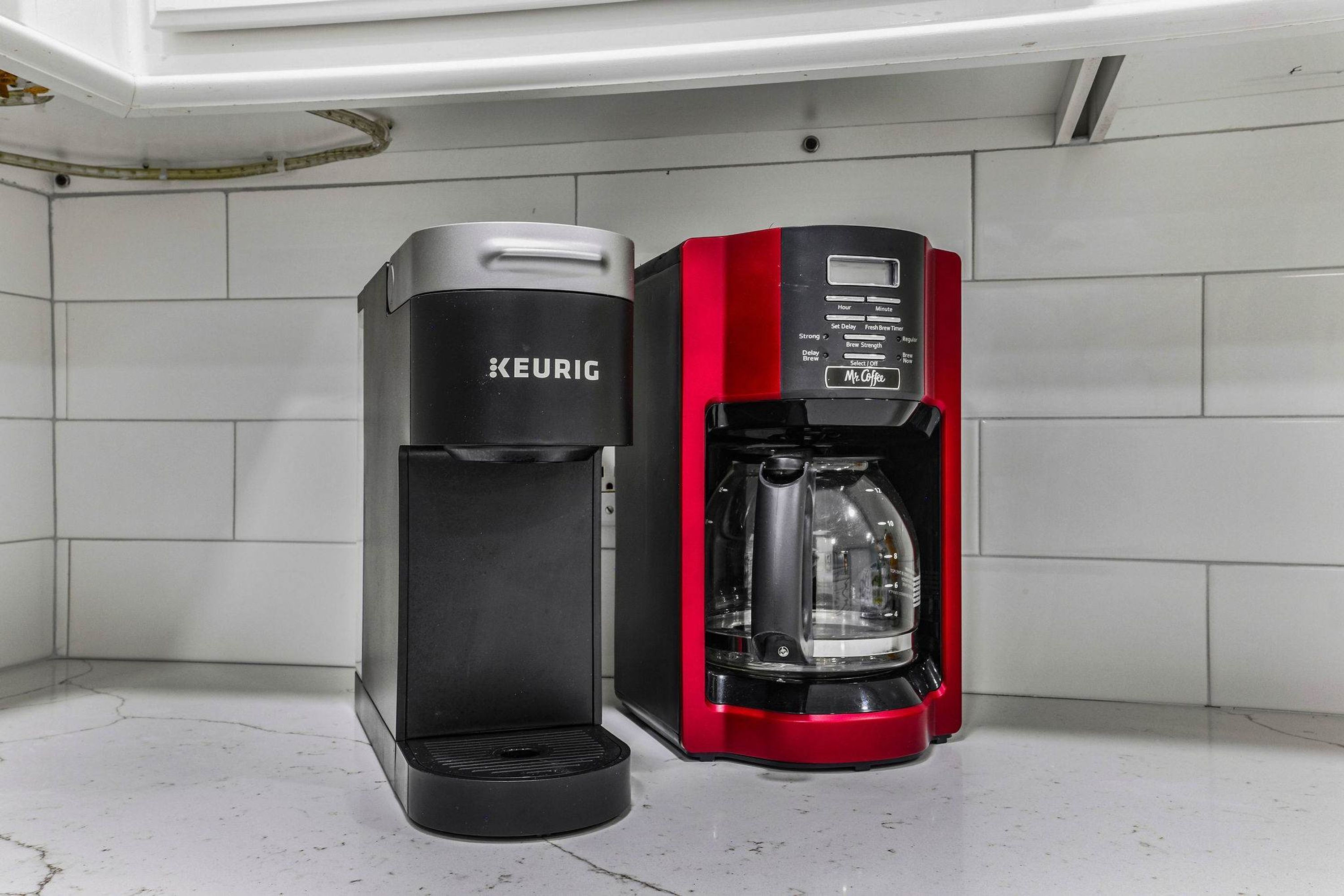 A KEURIG coffee maker and a red coffee machine on a kitchen counter.
