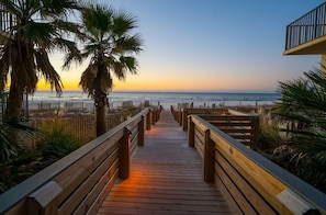 A wooden boardwalk leading to a beach with palm trees and a sunset view. - Palms 514- Beachfront Condo 2 2 5th Floor Beach Front Sleeps 8 (Orange Beach)