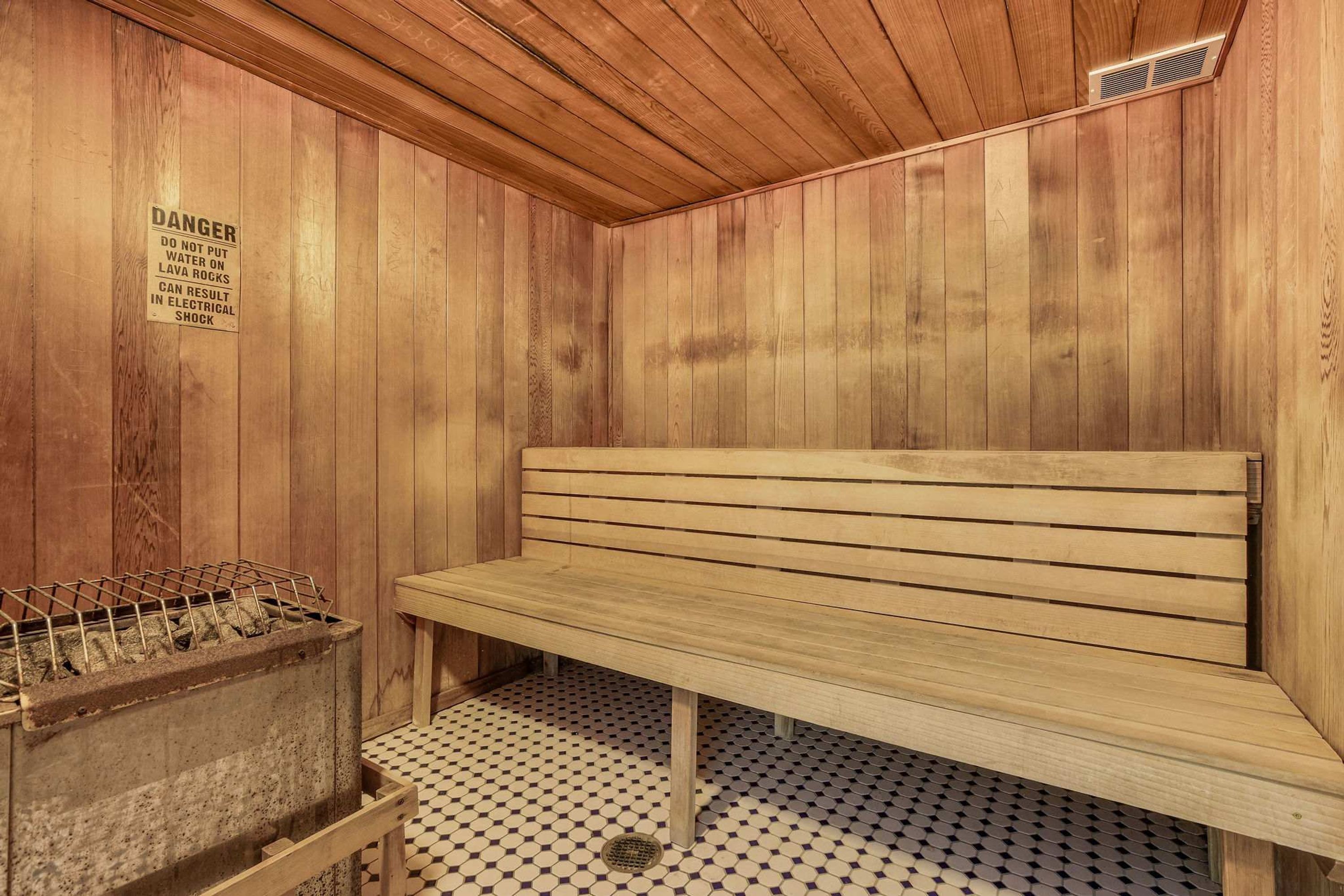 Un sauna avec des murs en bois, un banc et un panneau d’avertissement.