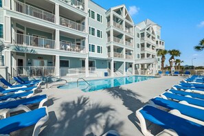Un hotel con varios balcones, piscina y tumbonas.