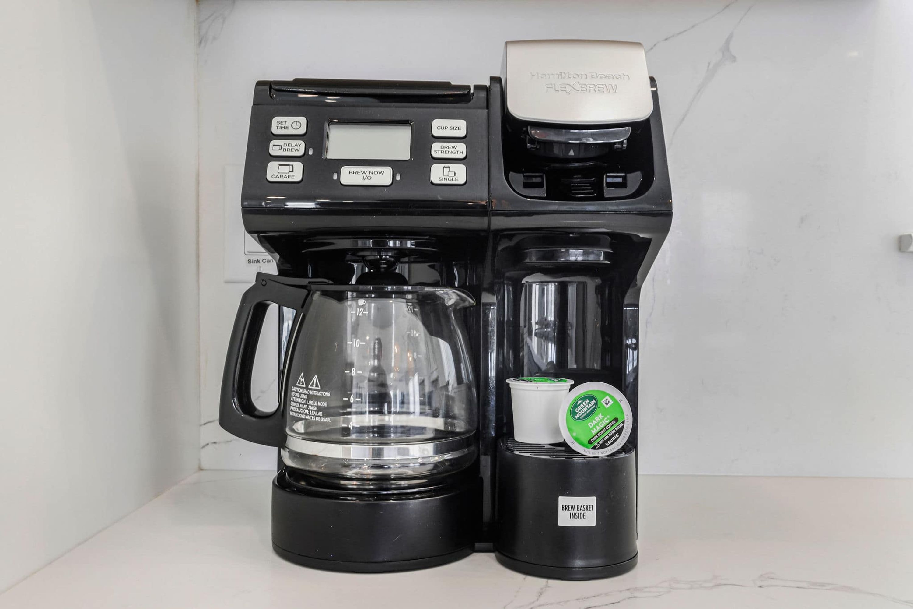 Uma cafeteira Hamilton Beach FlexBrew com uma bandeja coletora, uma jarra de café e uma cesta para filtro com tampa verde.