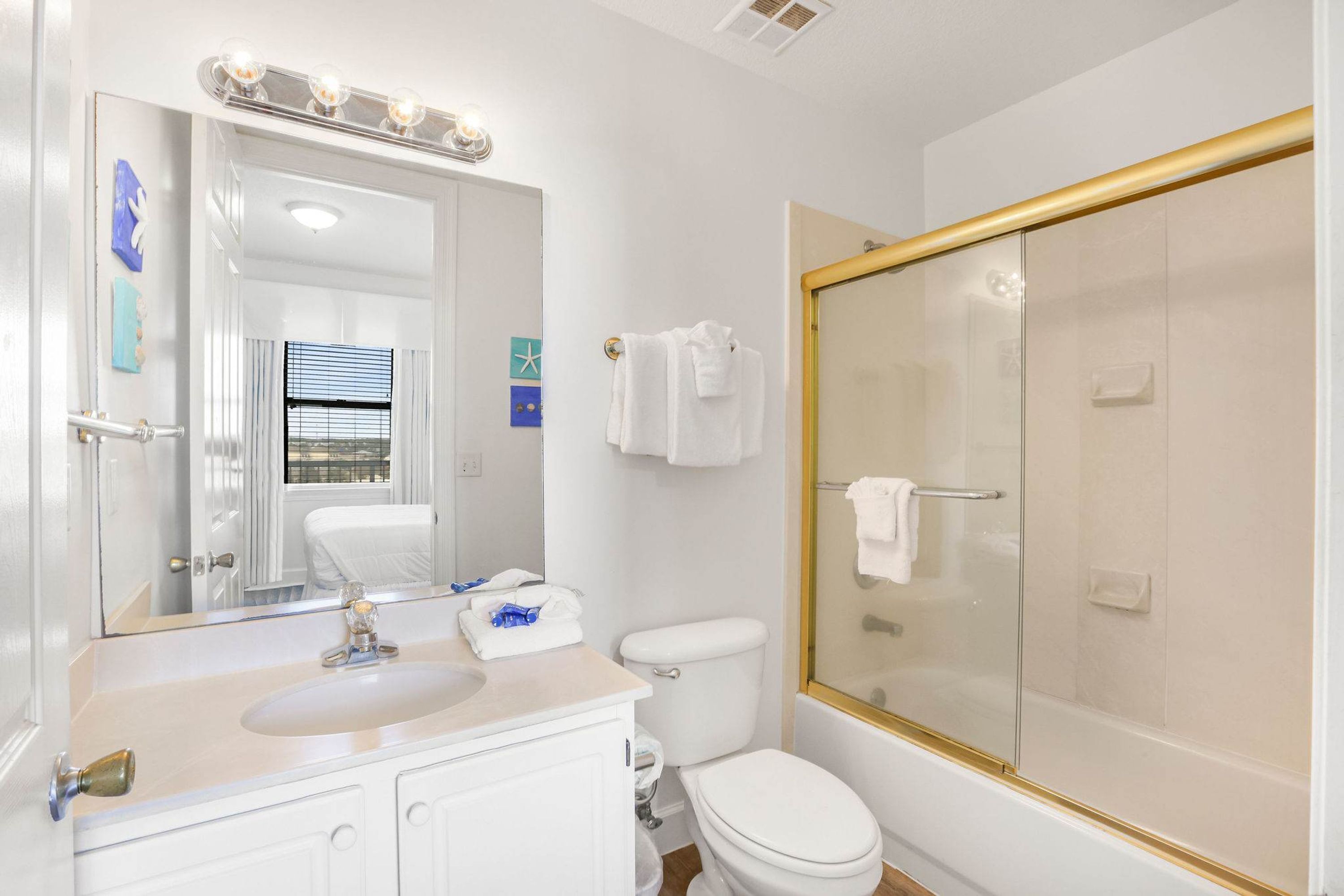 A bathroom with a sink, mirror, toilet, and glass-enclosed shower.