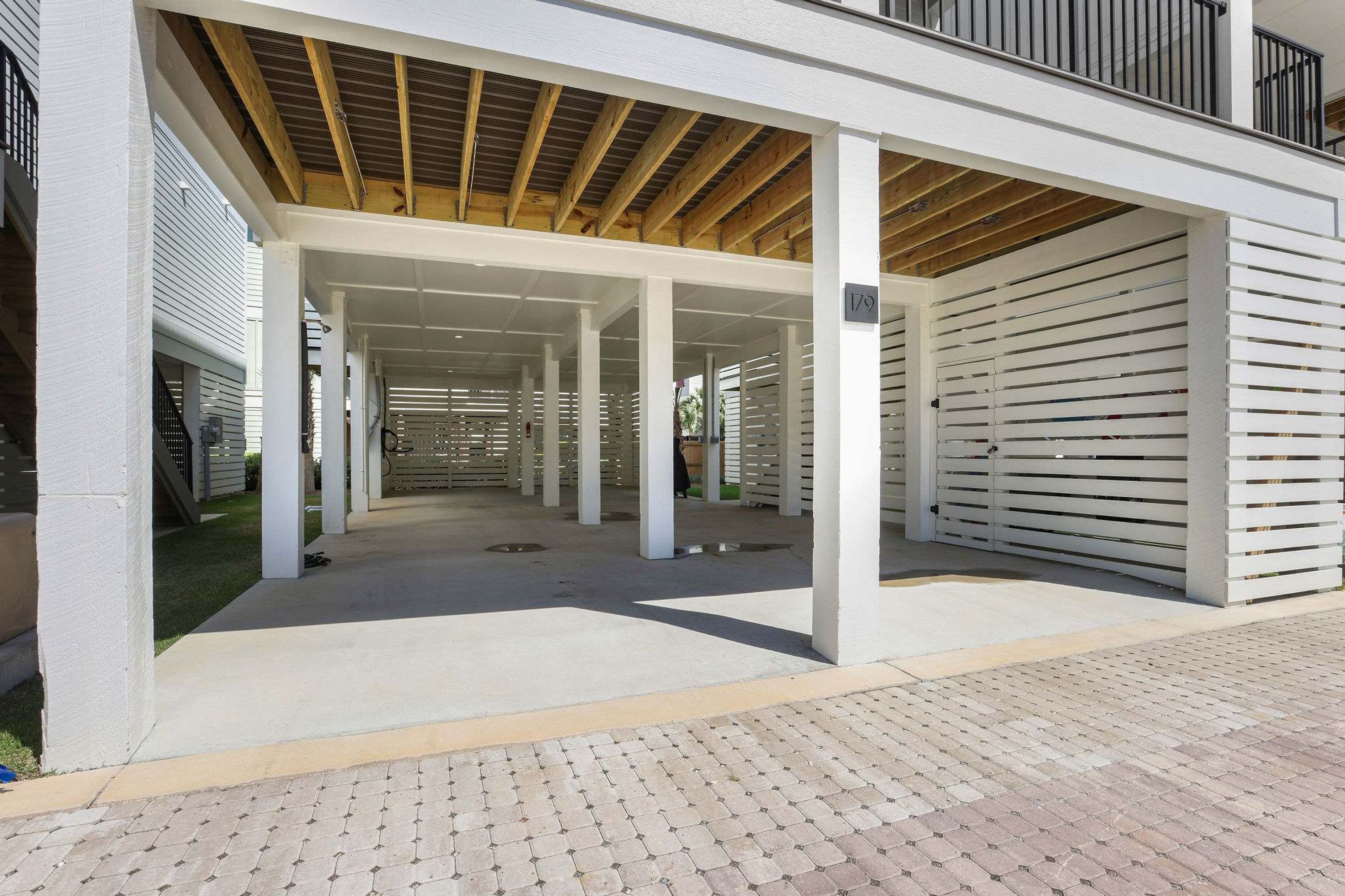 A covered outdoor area with a wooden ceiling, white columns, and a paved floor.