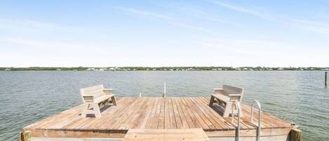 A wooden dock extending into calm water with a bench and a metal ladder.