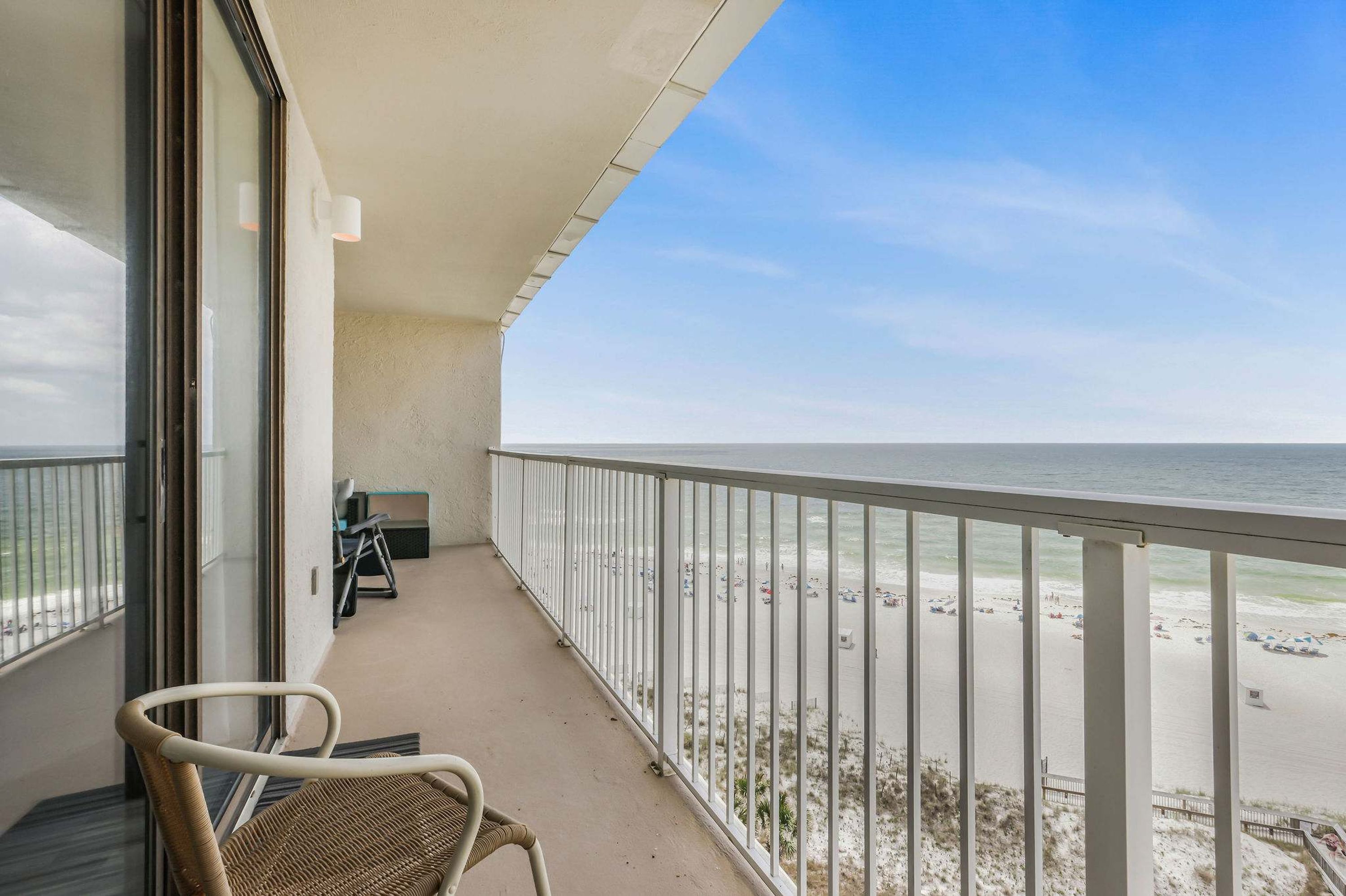 Un balcone con vista sulla spiaggia, una sedia e un tavolino.