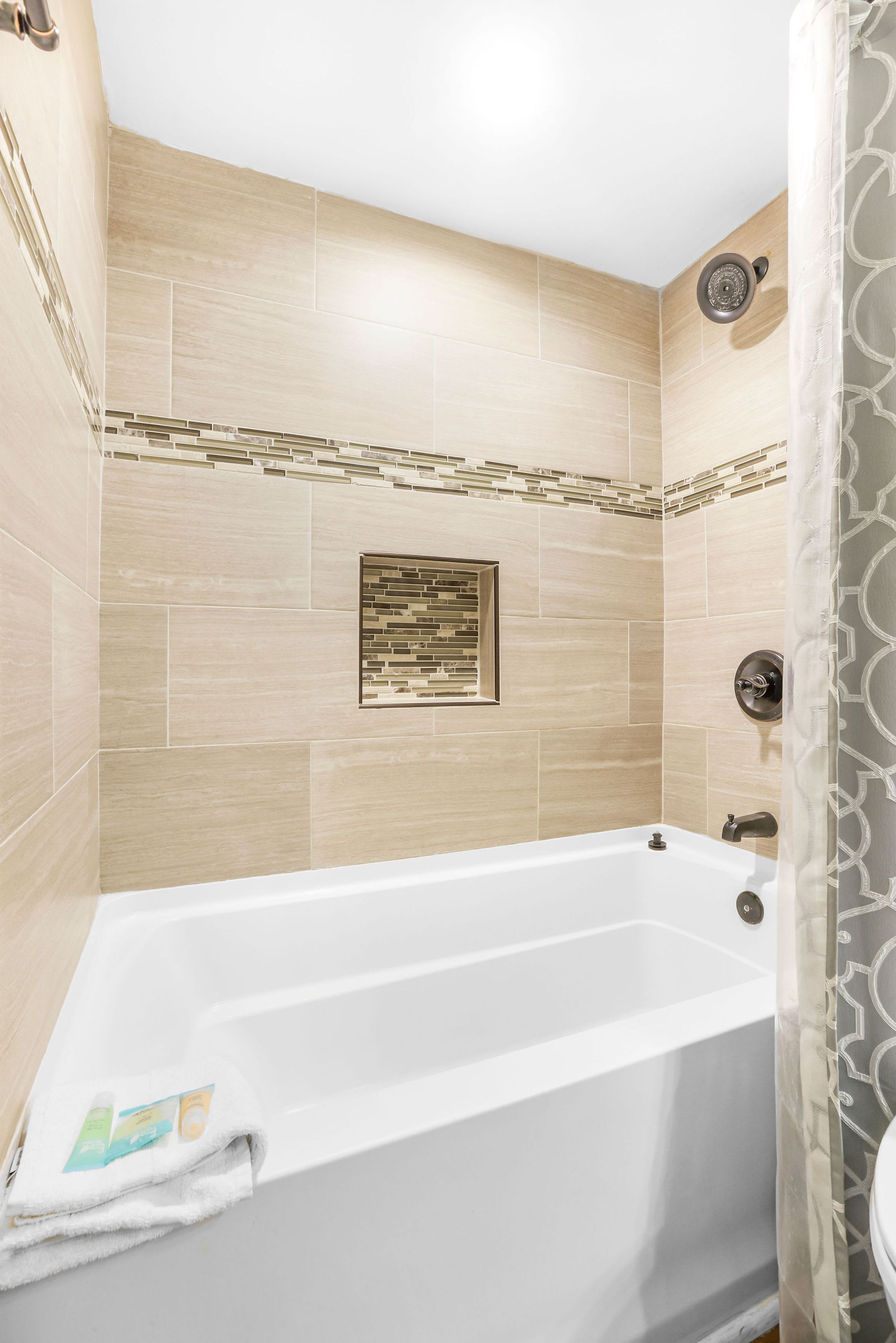 A modern bathroom with a bathtub, shower, and tiled walls.