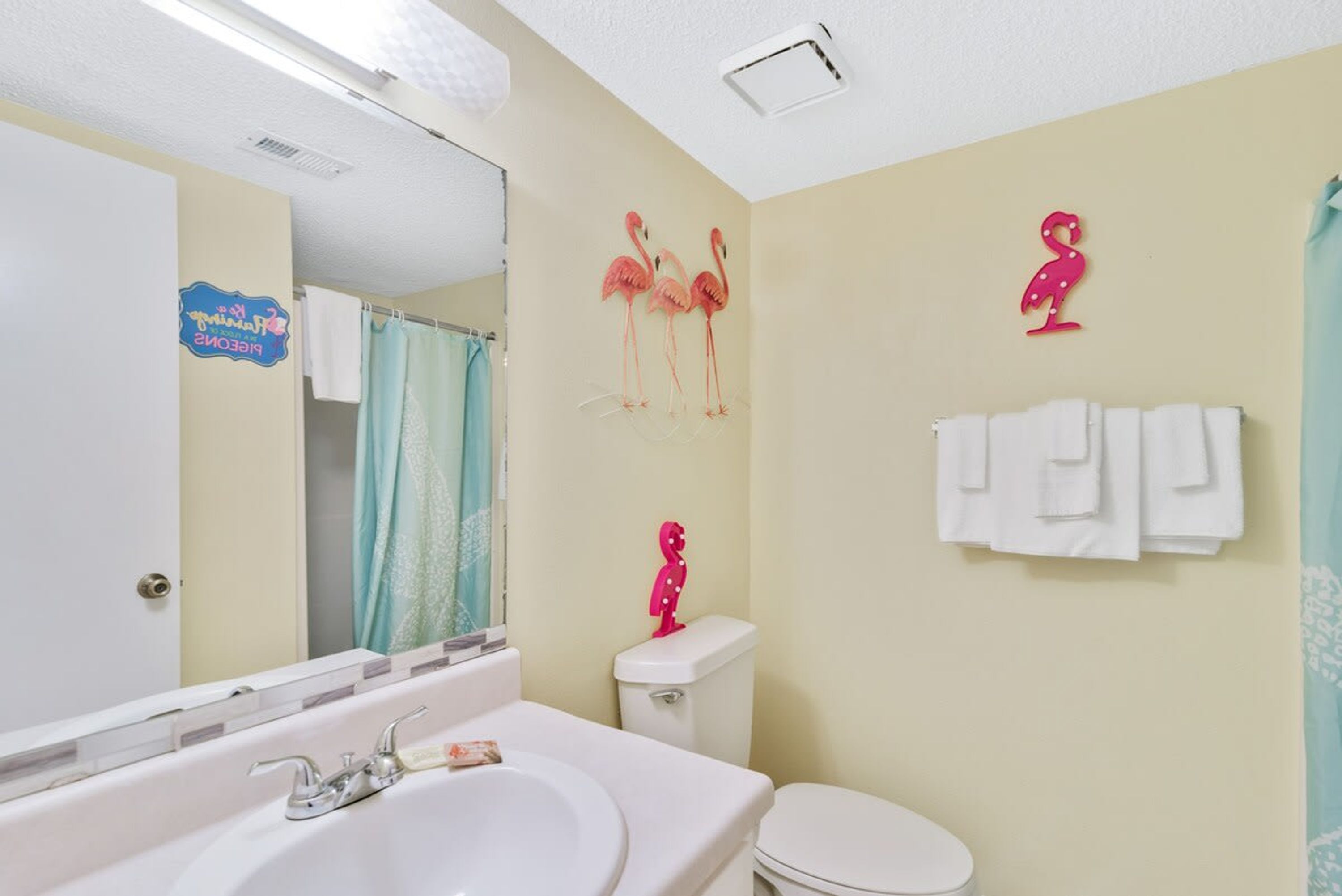 A bathroom with a white sink, a mirror, a toilet, and a shower curtain.