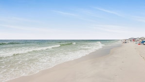 A beach with waves, a clear sky, and people in the distance. - Lagoon Landing 207- Best of Beach Lagoon (Gulf Shores)