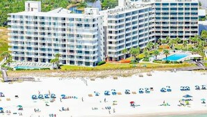 A beachfront hotel with multiple floors, a pool, and beach umbrellas. - Seaside Beach 2102- Beachside Ground Floor (Orange Beach)