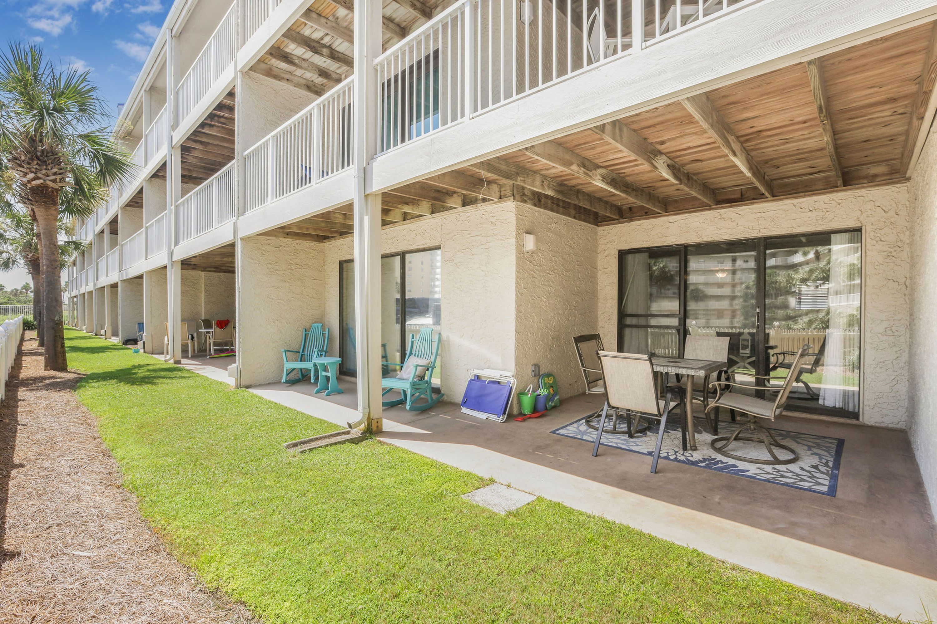 Un edificio de varios pisos con espacios exteriores para sentarse, incluidas mesas y sillas, y un patio cubierto.