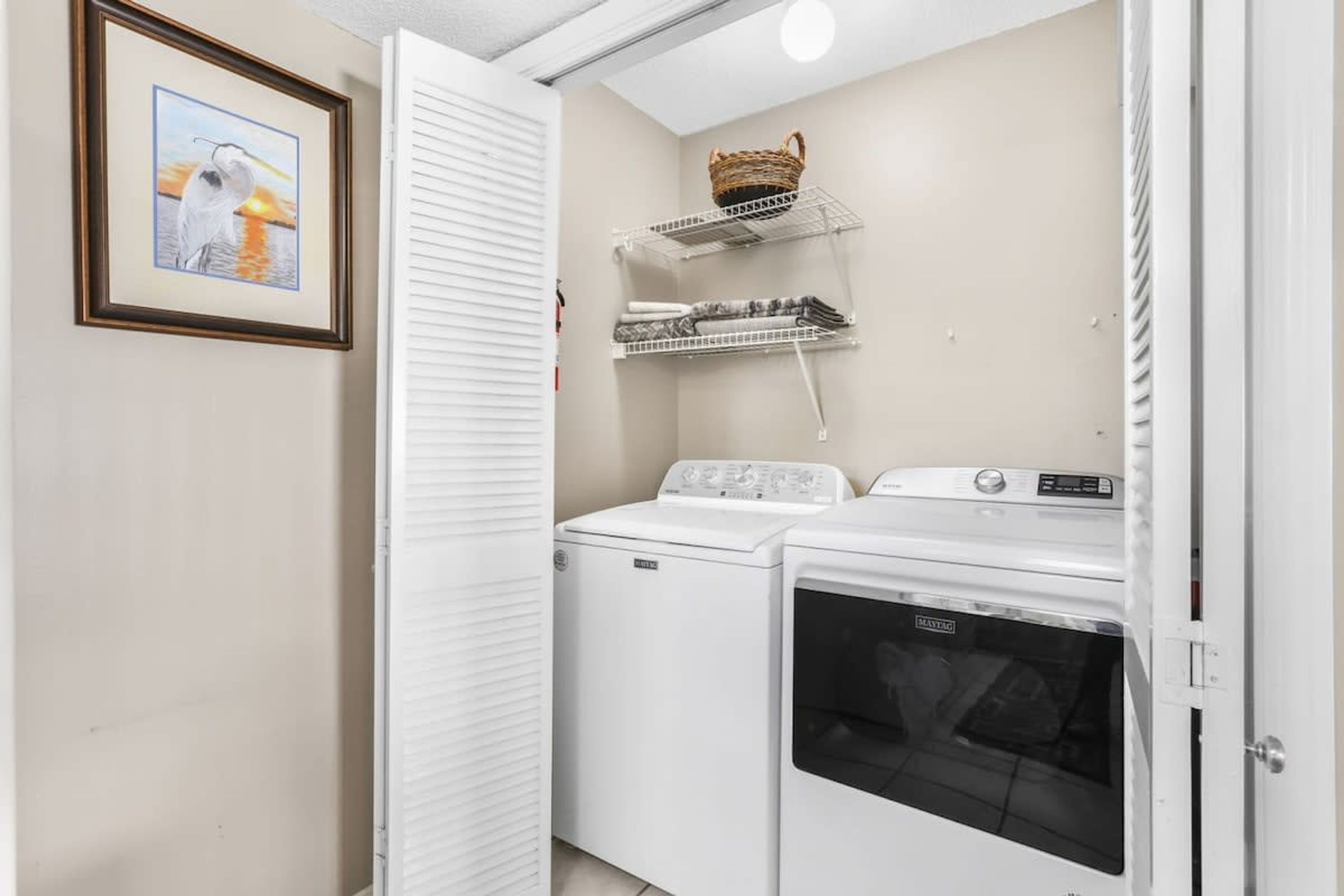 A laundry room with a washing machine, dryer, and shelves with baskets.