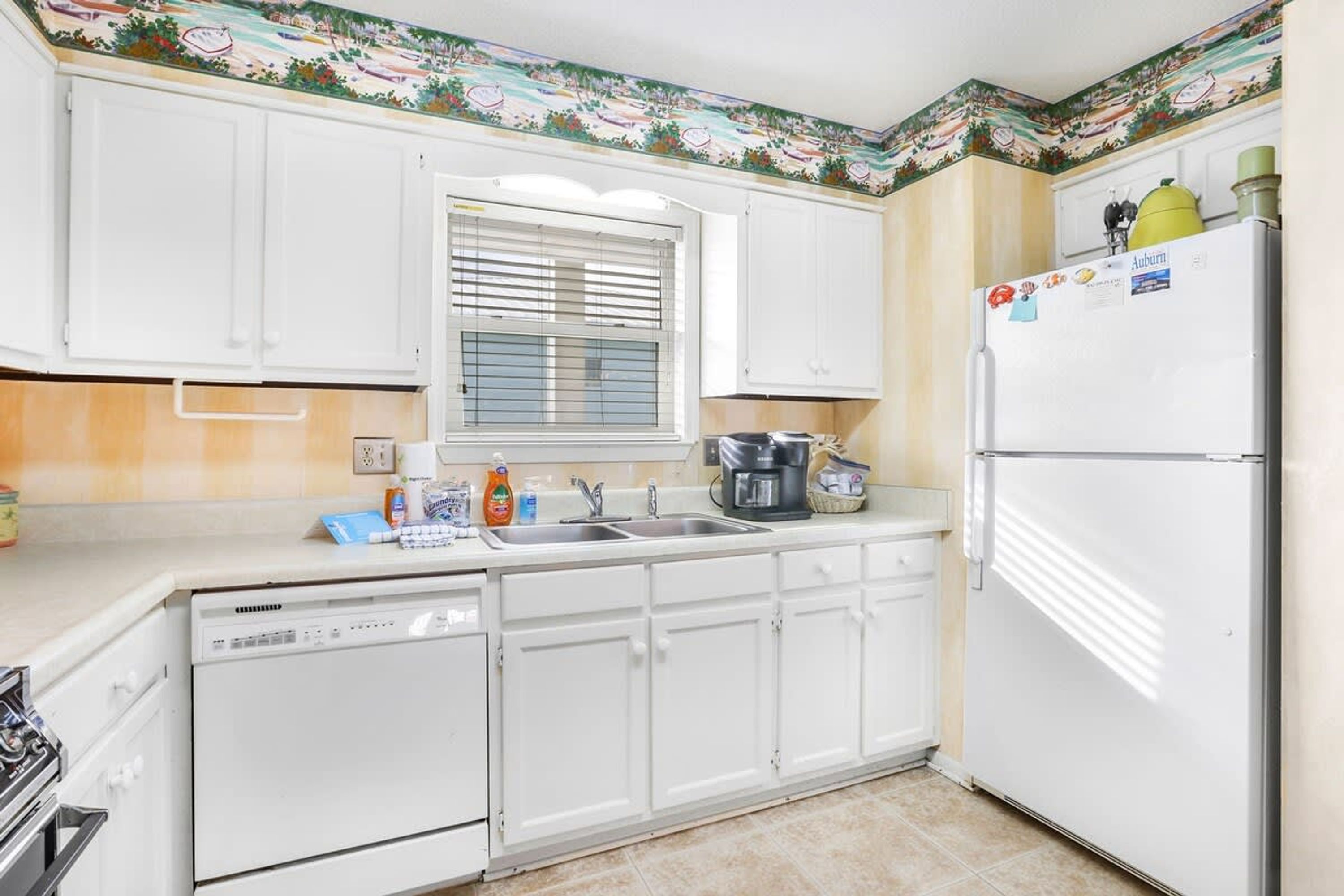 A kitchen with white cabinets, a window with blinds, a sink, a stove, and a refrigerator.