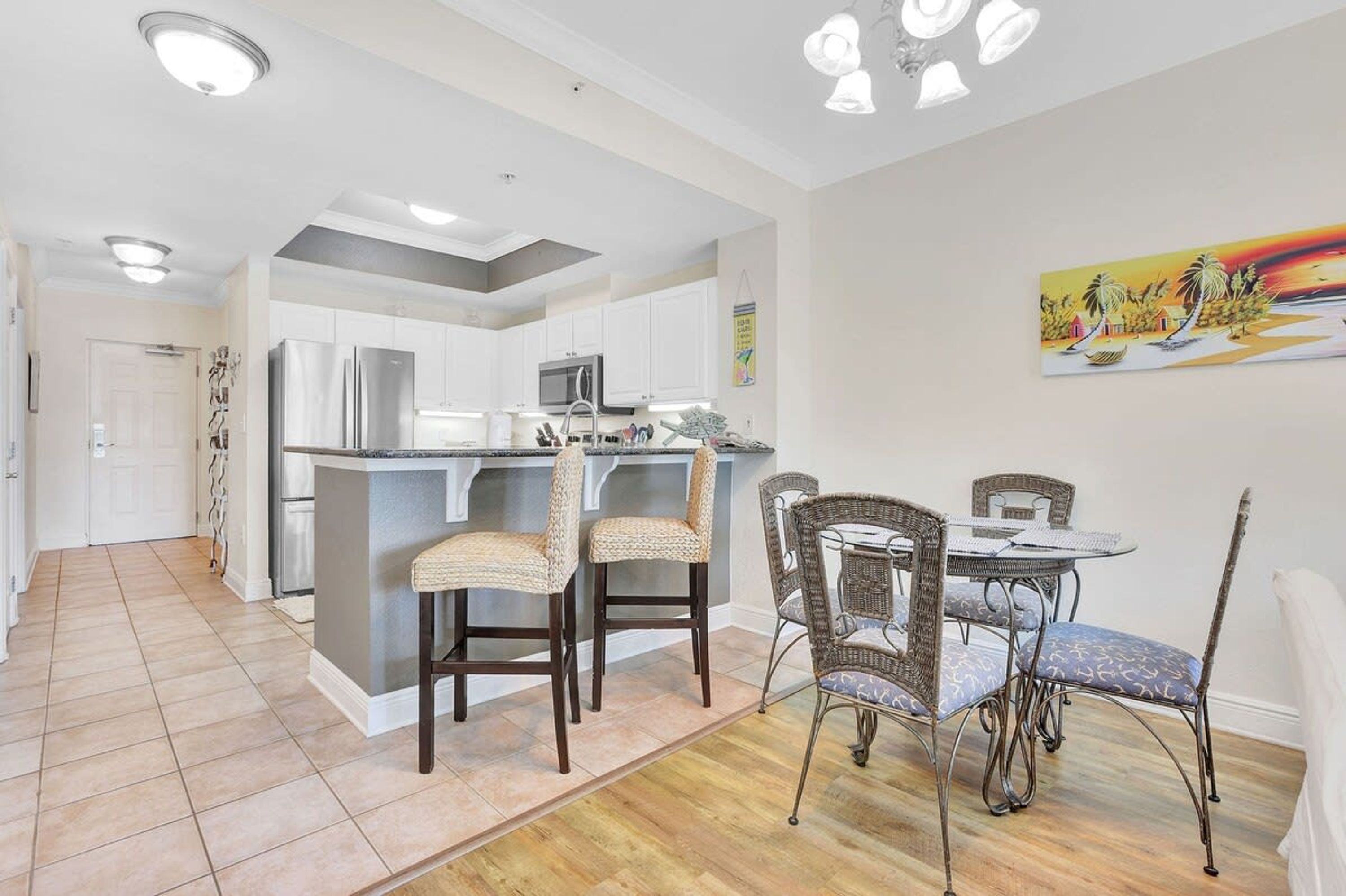 A modern kitchen with white cabinets, stainless steel appliances, and a central island with bar stools.