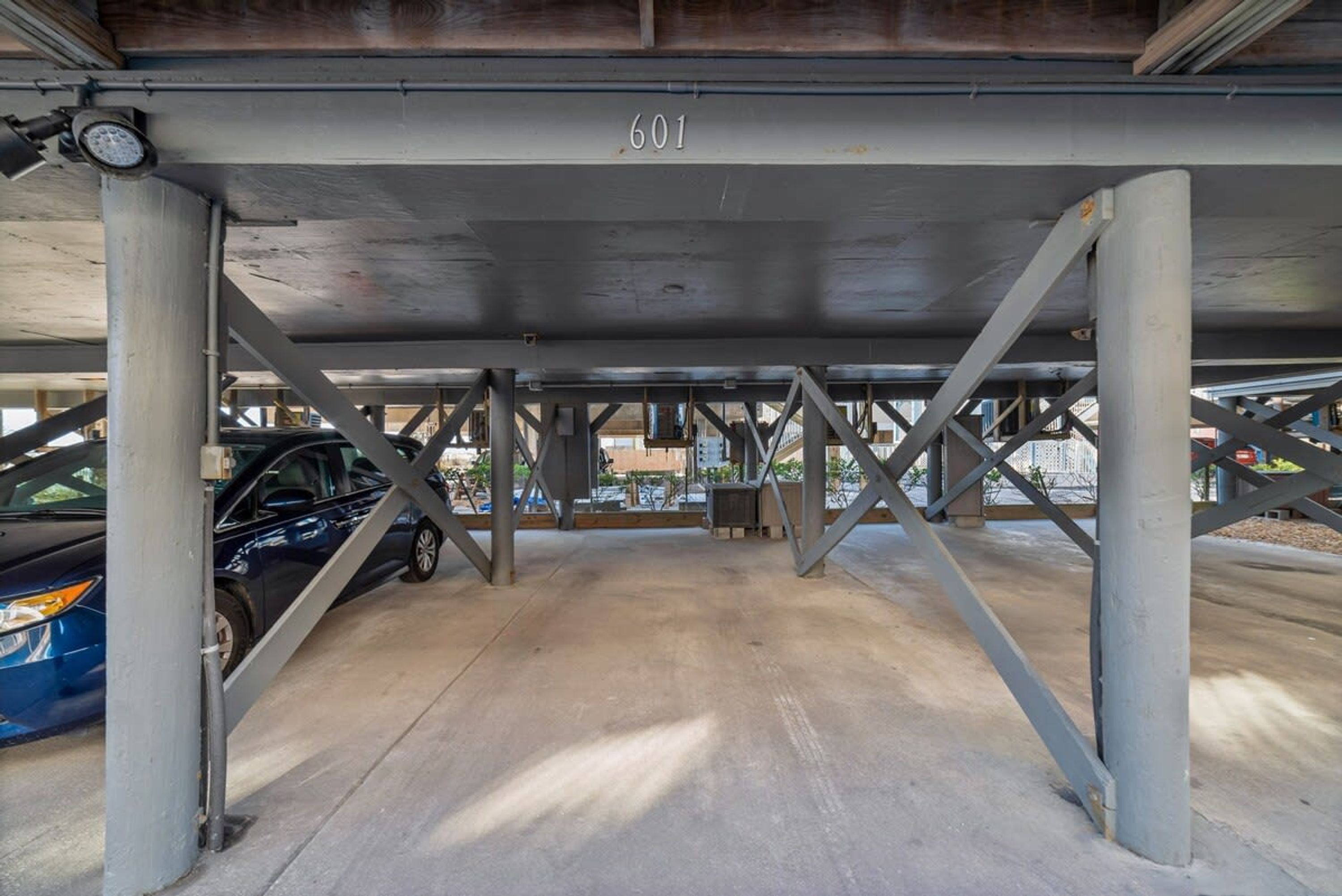 A parking garage with a concrete floor and metal beams.