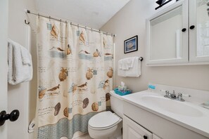 Ein Badezimmer mit Duschvorhang mit Meeresbewohnern, Toilette, Waschbecken und Spiegel.