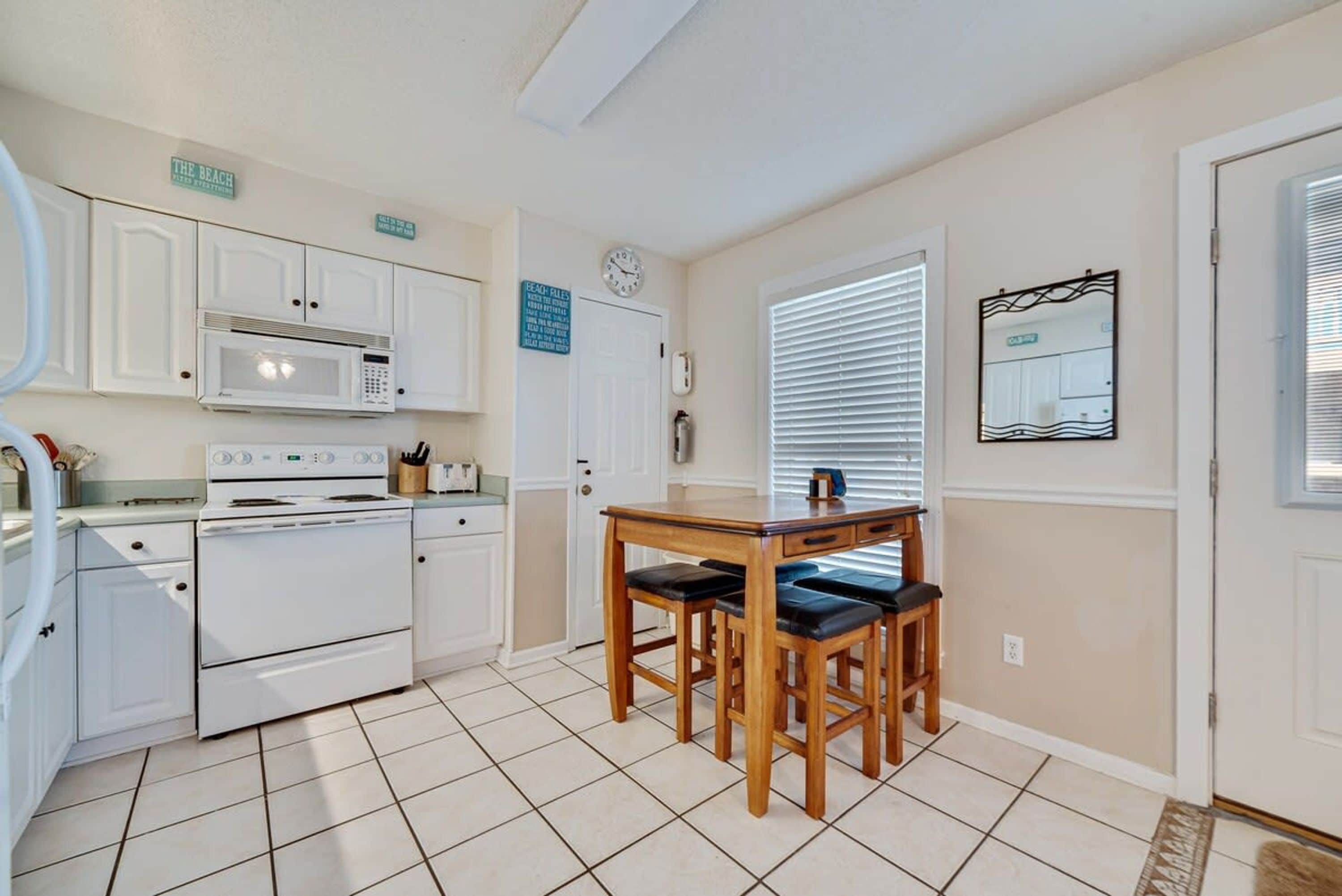 A kitchen with white cabinets, a microwave, a stove, and a wooden table with chairs.