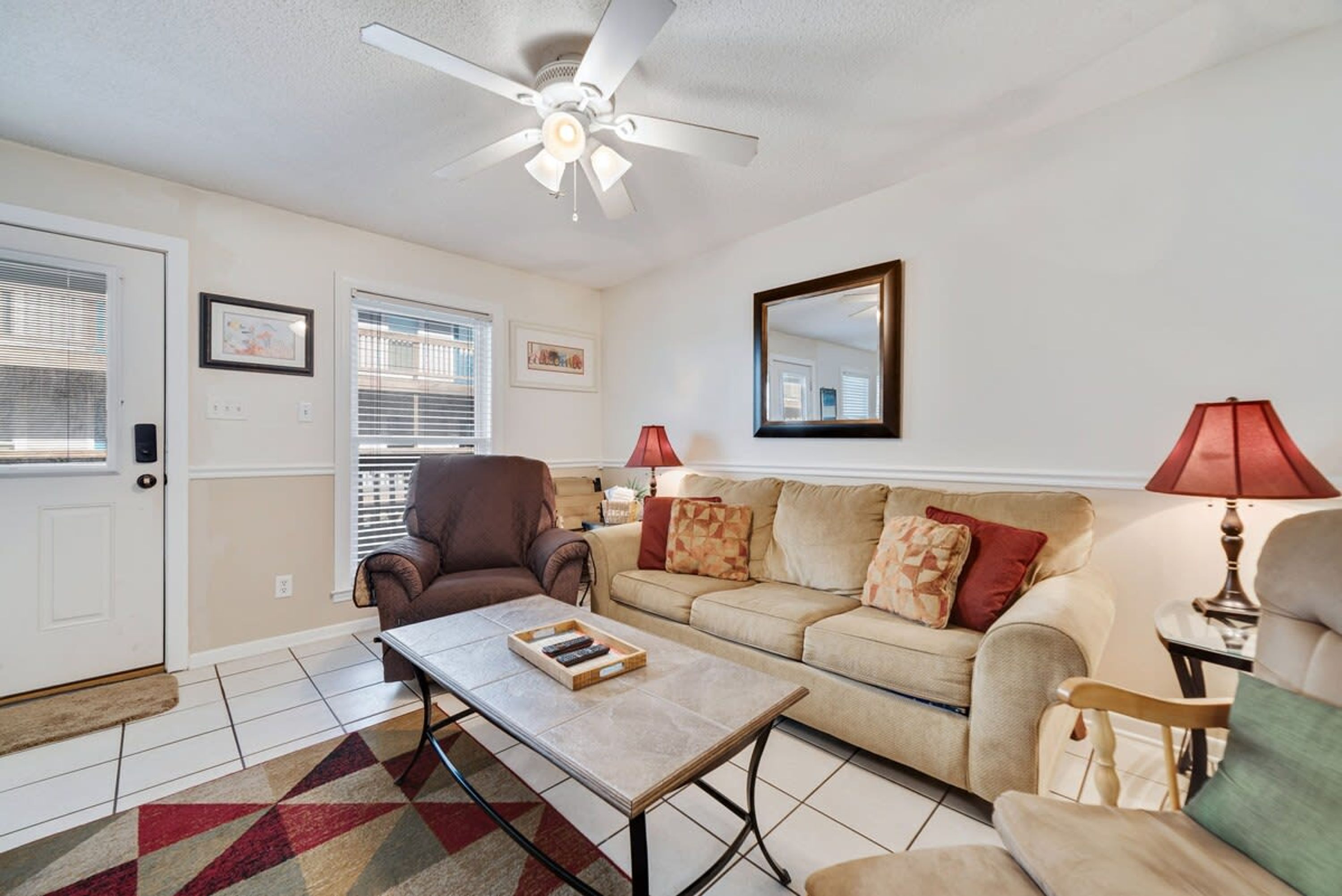 A living room with a sofa, armchair, coffee table, and a ceiling fan.