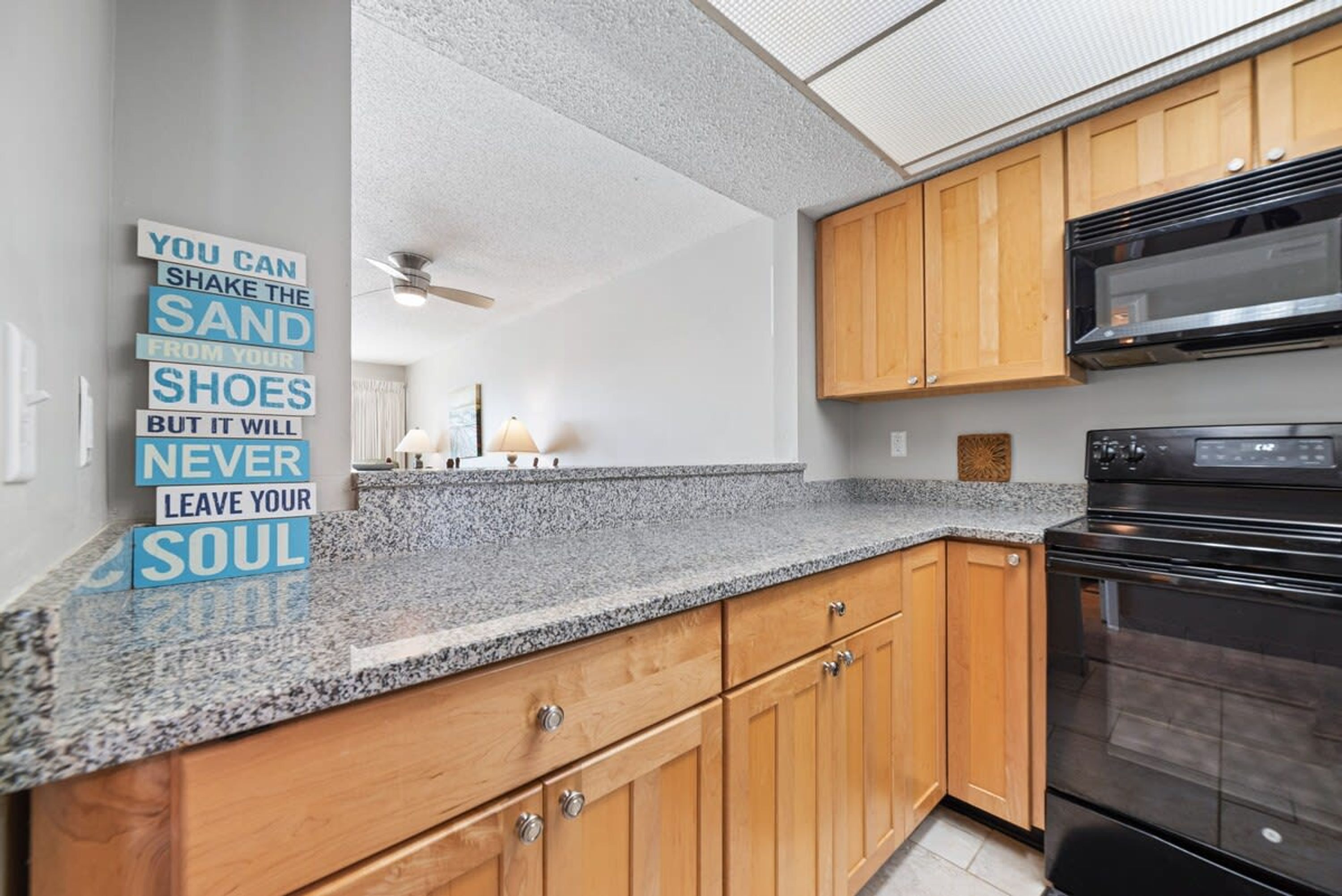 A kitchen with wooden cabinets, a granite countertop, and a black oven.