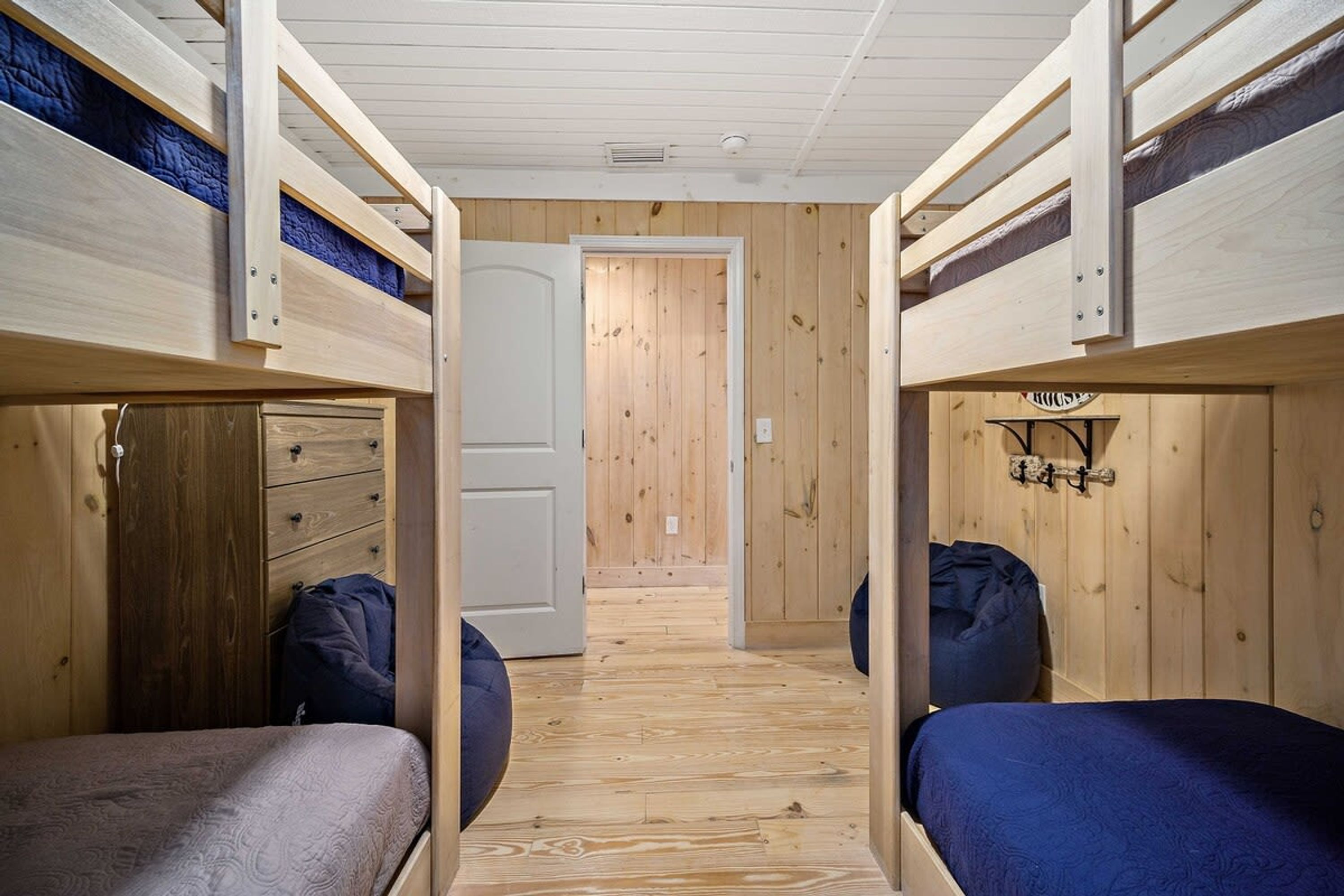 Een kamer met stapelbedden, houten wanden, een deur en een klein wandplankje.