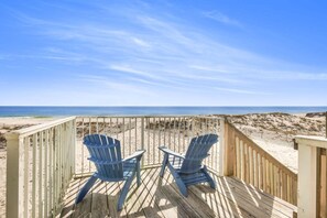 A wooden deck with two Adirondack chairs overlooking a beach. - Sunrise Village 215- 2BR 1BA Gulf Front Sleep 6 (Gulf Shores)