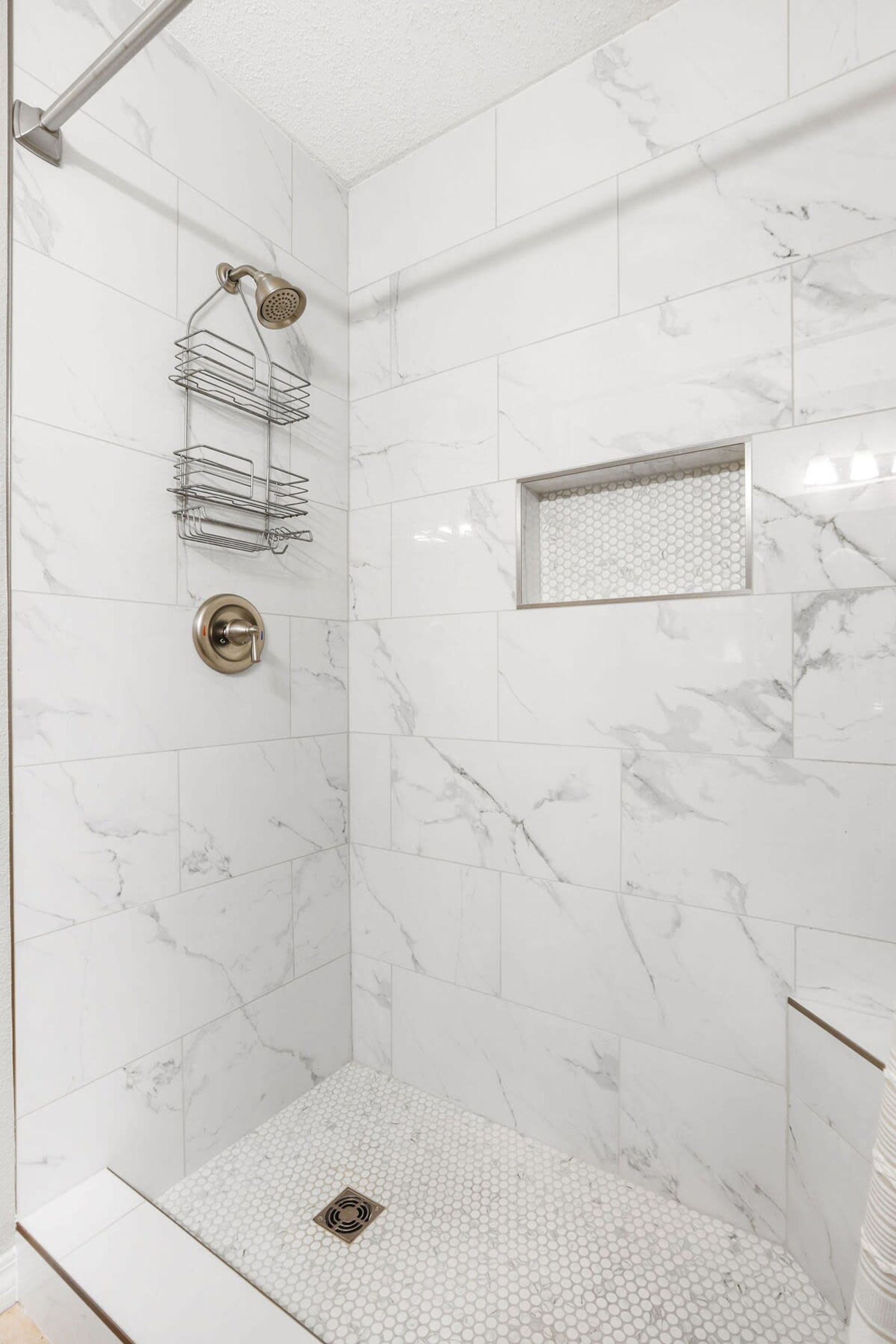 A modern shower with a rain showerhead, a handheld showerhead, and a wall-mounted towel rack.
